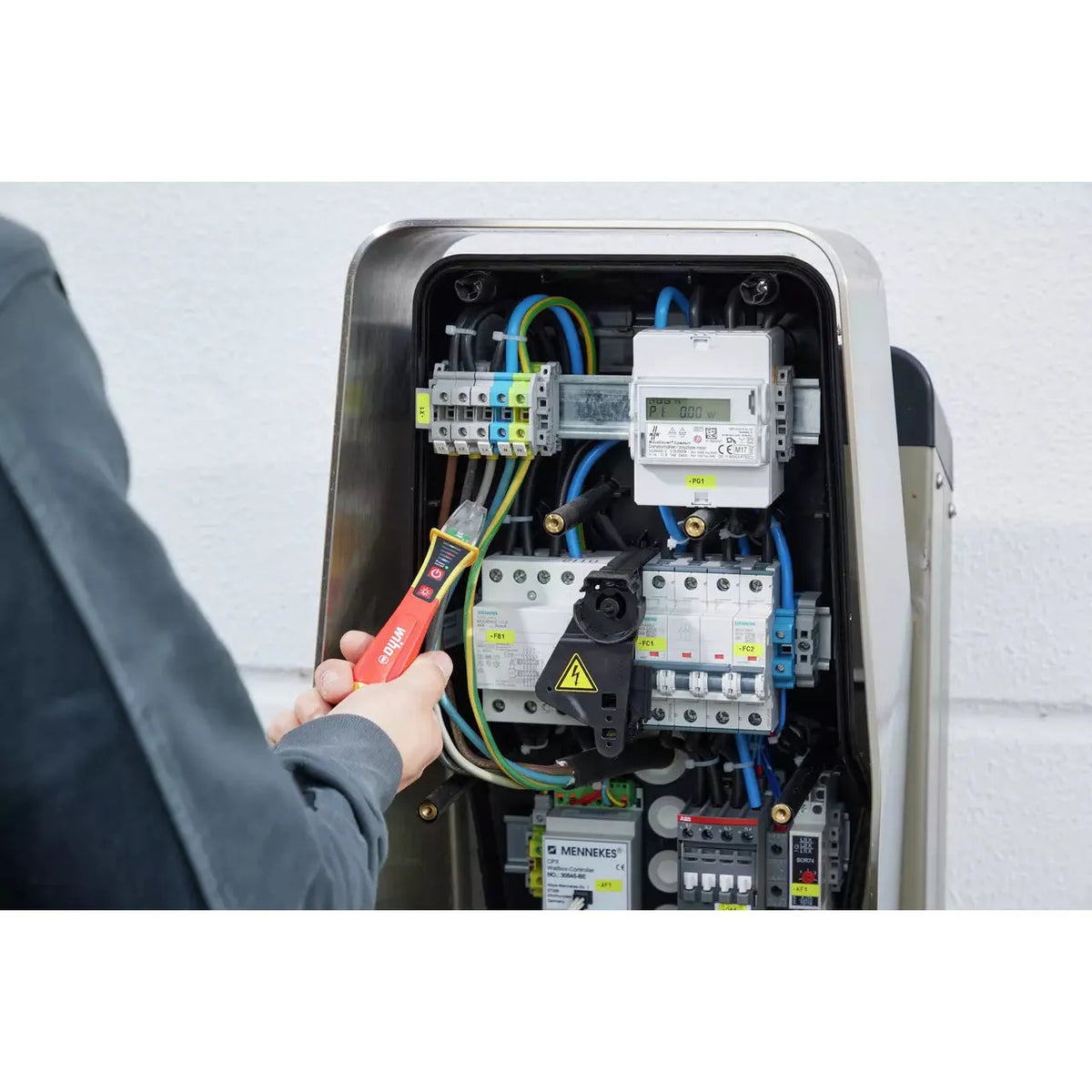 12–1,000V AC – Person using a non-contact voltage detector on electrical panel