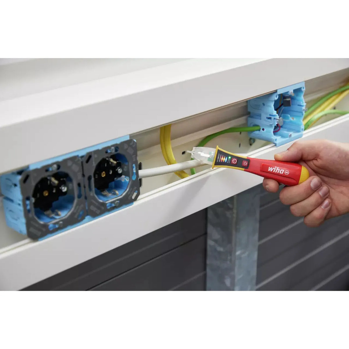 12–1,000V AC – Hand using a red non-contact voltage detector near electrical wires in a cable channel.