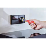 12–1,000V AC – Hand using a non-contact voltage detector near a black wall socket.