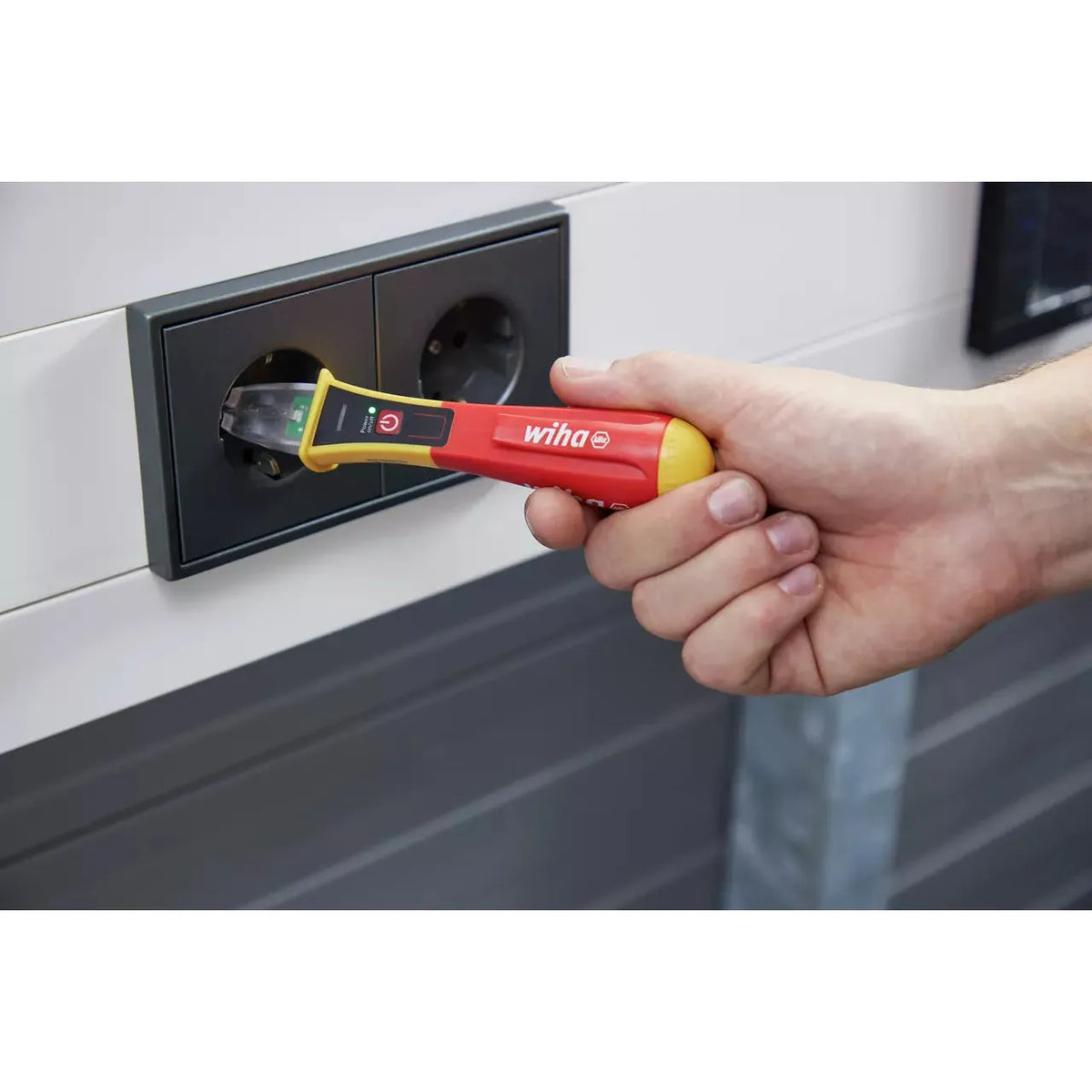 90–1,000V AC – Hand using non-contact voltage detector in power outlet