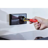 90–1,000V AC – Hand using a red and yellow voltage detector on a black wall socket.