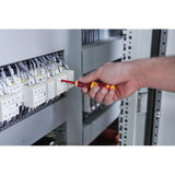 A person uses an insulated screwdriver on an electrical panel with multiple wires and switches.