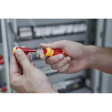 Hands holding an insulated bit and an electric screwdriver handle in red and yellow.