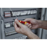Person using a red and yellow electric screwdriver near an electrical panel.