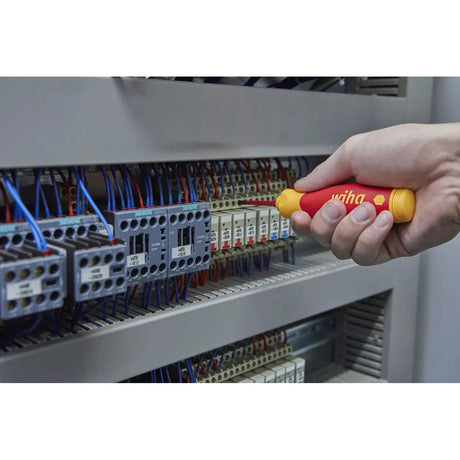 Person using an electric screwdriver on a circuit breaker panel.