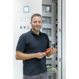Person holding a red electric screwdriver in front of an open electrical panel.