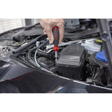 Person using a screwdriver on a car engine part.