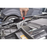 A person uses a screwdriver in a car engine compartment.