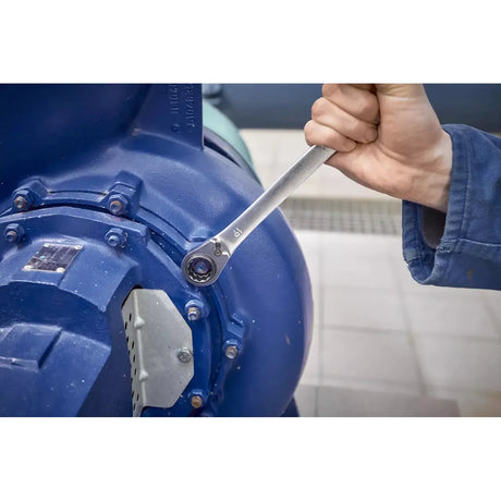 A person using a ratchet wrench to tighten a bolt on a large blue machine.