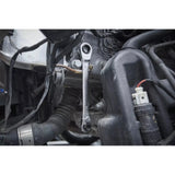 A ratchet wrench is being used on a bolt in a car engine area.