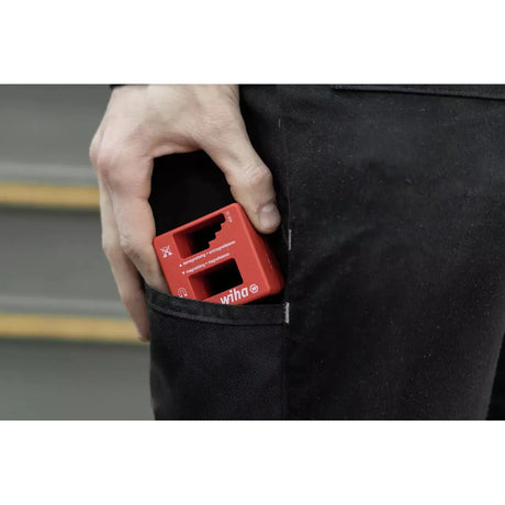 A person placing a red magnetizer tool into a pocket.
