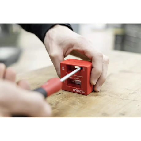 Hand using red magnetizer on screwdriver