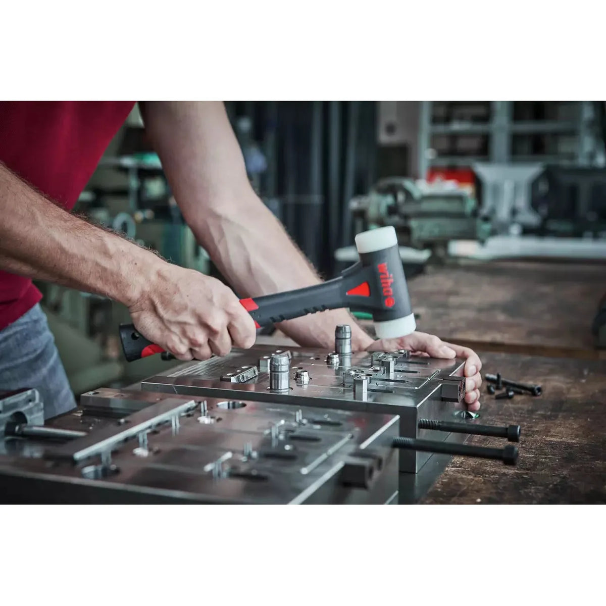 Person using a dead-blow hammer on a metal assembly