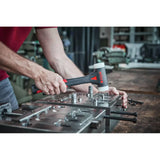 Person using a dead-blow hammer on a metal assembly. The hammer has a black handle and white striking faces.