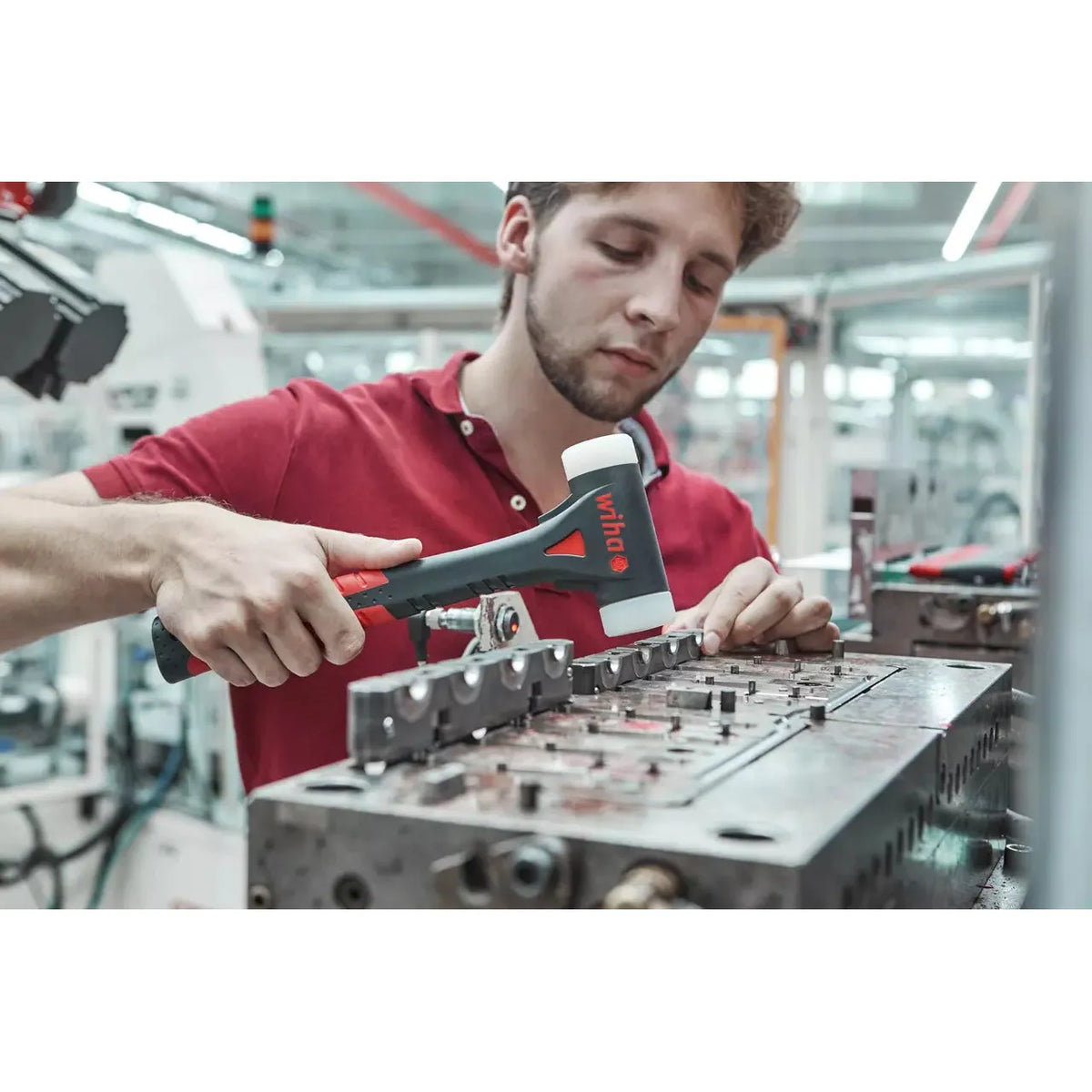 A person using a dead-blow hammer in a workshop setting.