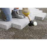 Person using a rubber mallet to lay paving stones on gravel