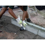 Person using a rubber mallet to adjust a concrete slab on a construction site.