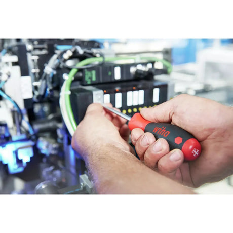 Person using a red and black screwdriver on electronic equipment.