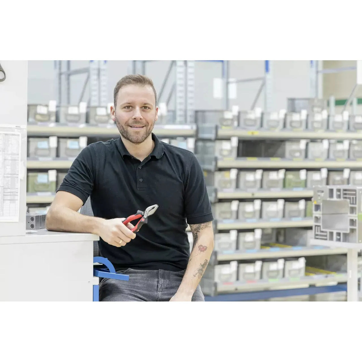 Person holding combination pliers in a warehouse