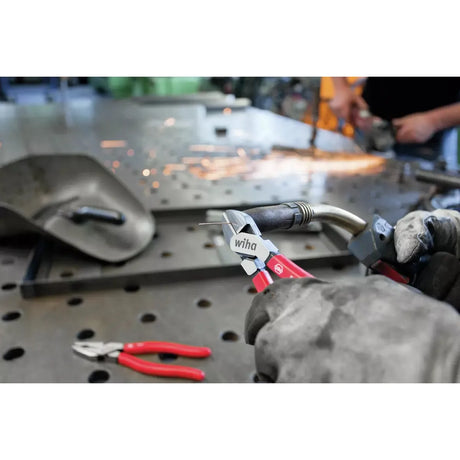 Person using diagonal cutter to trim wire on metal surface