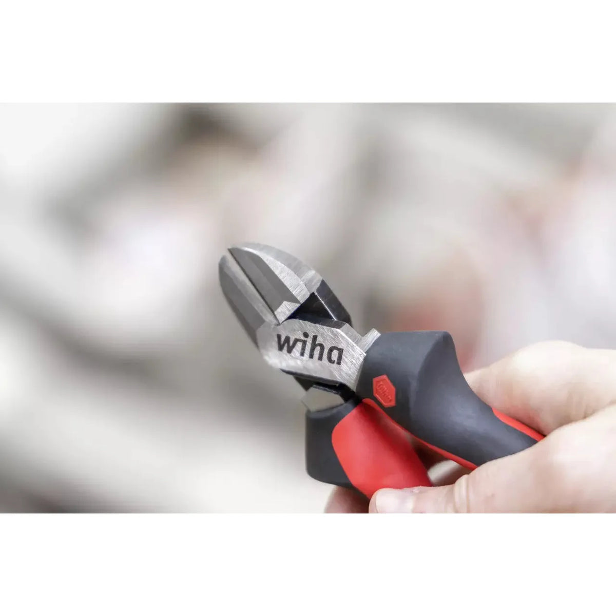 Wire cutter with red and black handles held in a hand.