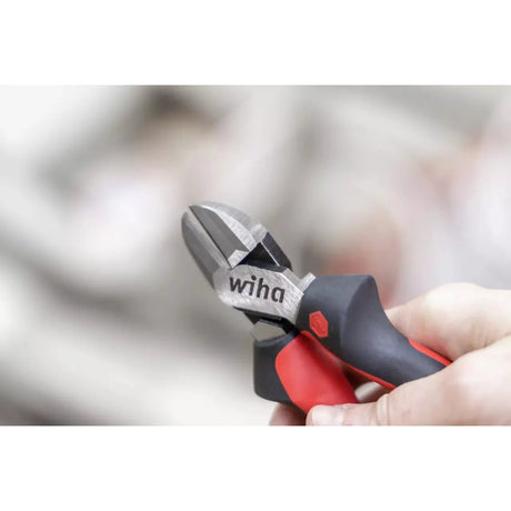 Wire cutter with red and black handles held in a hand.