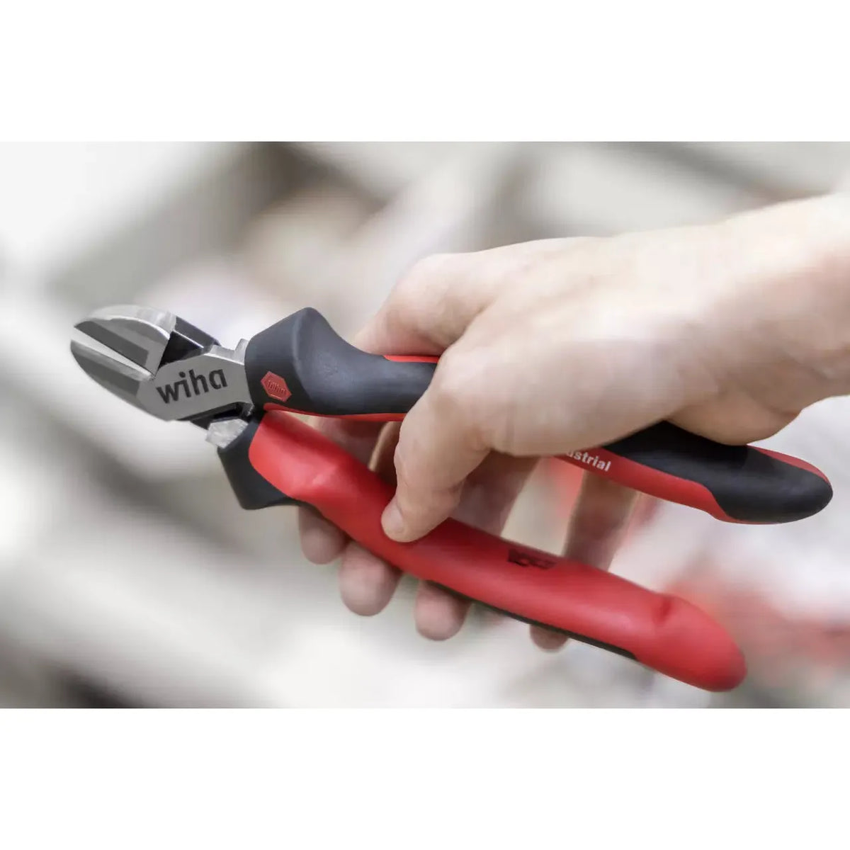 Hand holding red and black wire cutters with a metal blade