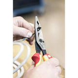 Person using pliers with red and yellow handles to strip insulation from electrical wires.