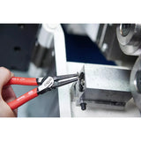 A person uses snap ring pliers to adjust a metal component.