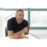 A person holding red-handled pliers, with more pliers on the table