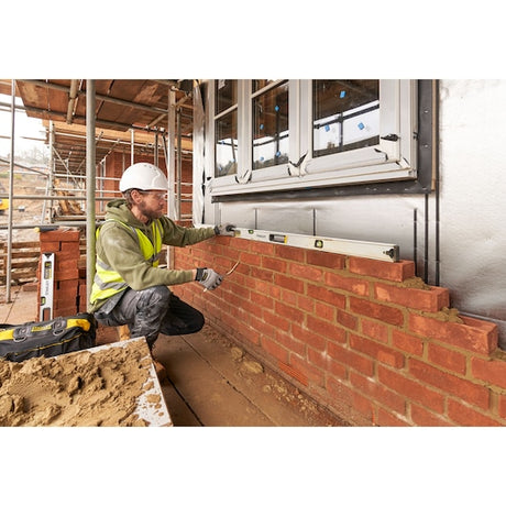 STANLEY FMHT43678-1 spirit level used by a worker checking horizontal alignment on a brick wall, side view.