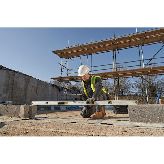 STANLEY FMHT43678-1 spirit level used by worker in safety gear on construction site, outdoor scene.