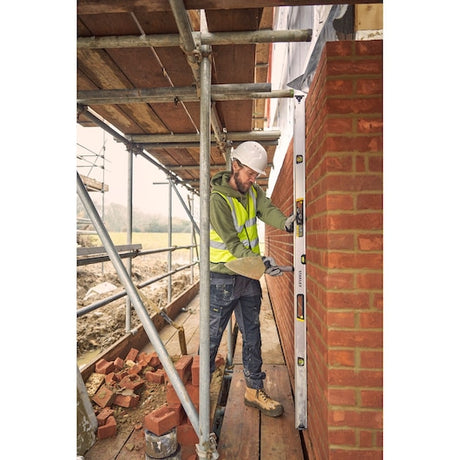 STANLEY FMHT43678-1 spirit level in use by worker checking vertical alignment of brick wall on construction site.