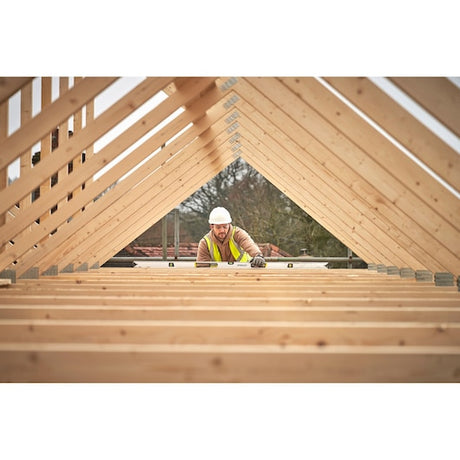 STANLEY FMHT43678-1 spirit level used by worker on wooden roof trusses, construction site view.