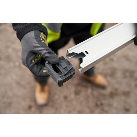 STANLEY FMHT43678-1 level clamp held by gloved hand near metal rail, angled outdoor photo.