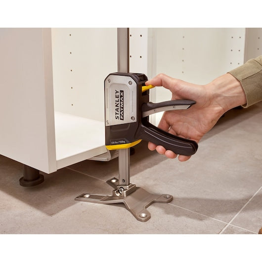 STANLEY FMHT83550-1 cabinet jack tool in use, photo shows hand gripping handle on tiled floor.