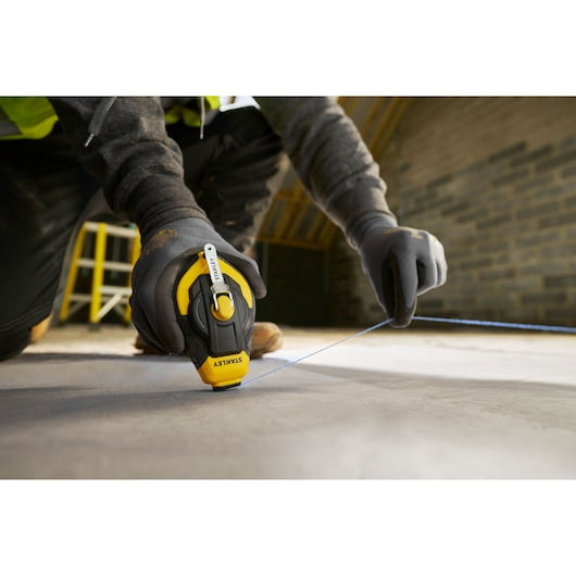 Photo of STANLEY STHT47311-0 chalk line tool in use, worker marking line on concrete floor.