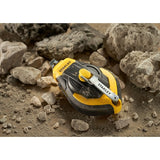 STANLEY STHT47311-0 chalk line reel, black and yellow, shown on dusty rocks.