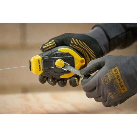 STANLEY STHT47311-0 chalk reel held in gloved hands, yellow and black design, product in use.