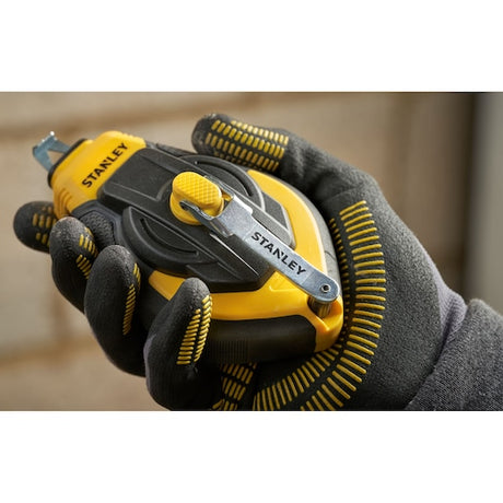 Stanley STHT47311-0 chalk line reel held in gloved hand, yellow and black casing, side view.