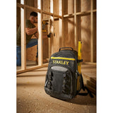STANLEY STST1-72335 black tool backpack with yellow accents and level, on construction site floor.