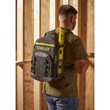 Stanley STST1-72335 black and yellow backpack worn by a man in a workshop, holding a level tool.