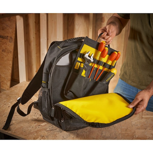 STANLEY STST1-72335 tool backpack with yellow interior, filled with hand tools, shown open on a work surface.
