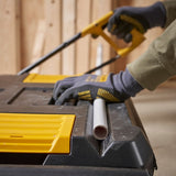 STANLEY STST1-80150 toolbox used as a work surface, person in gloves sawing a pipe, close-up photography.