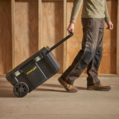 Photo of a STANLEY STST1-80150 rolling tool box being pulled by a person on a construction site.